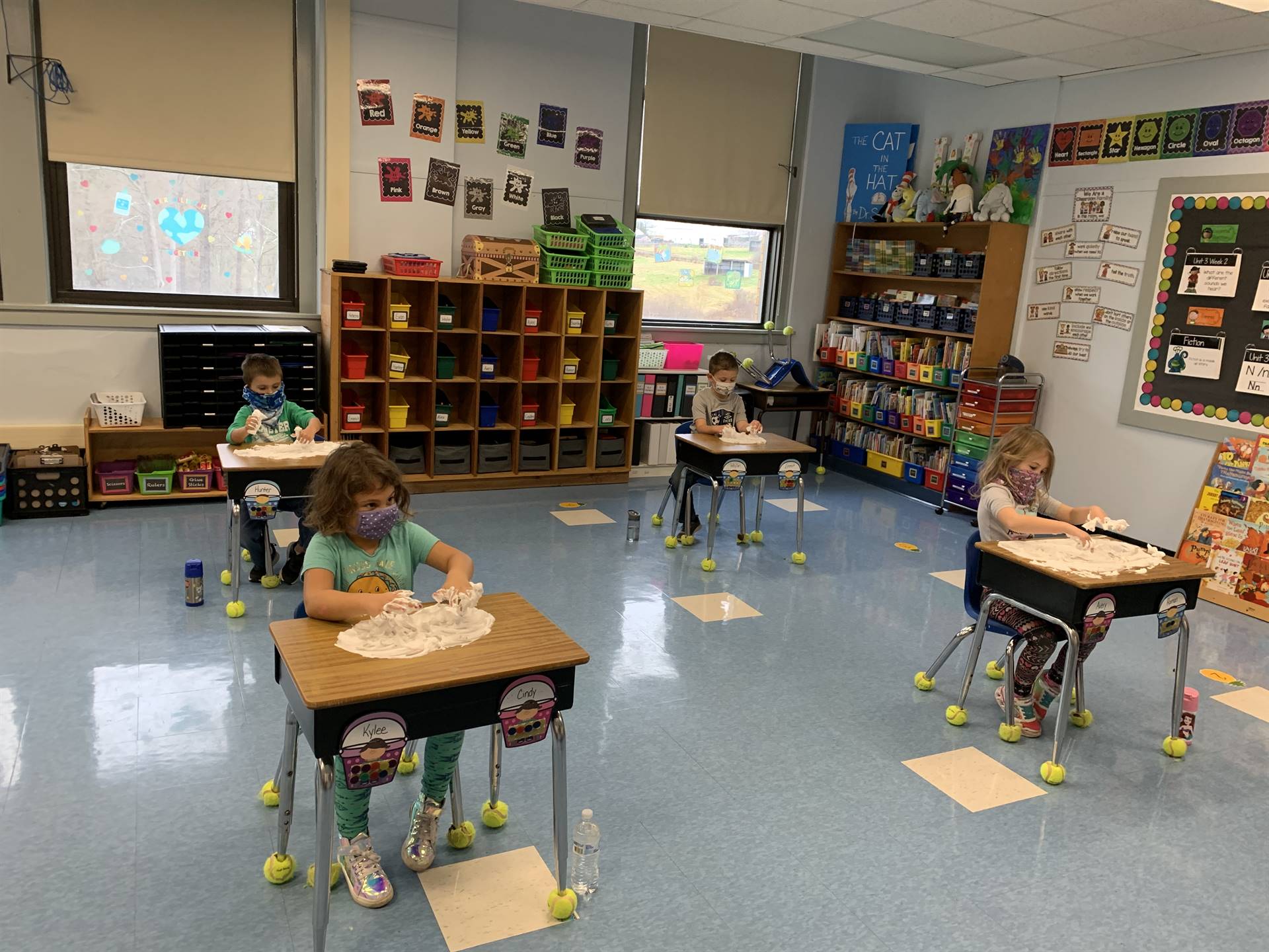 students at desks writing numbers in shaving cream.