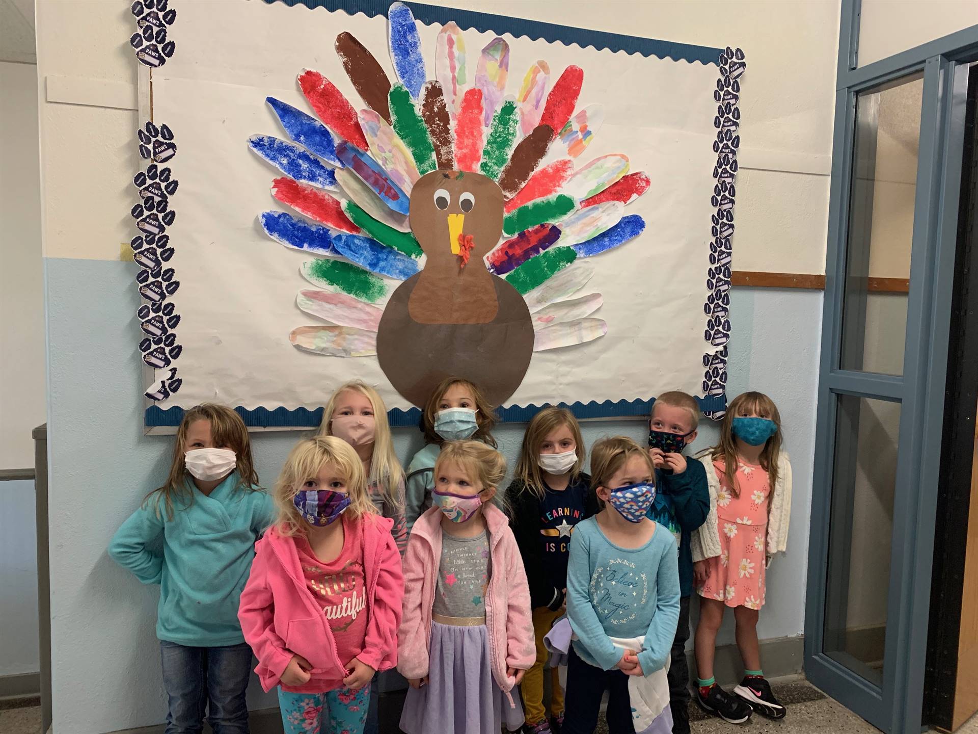 Pre K students stand by Teamwork turkey bulletin board!