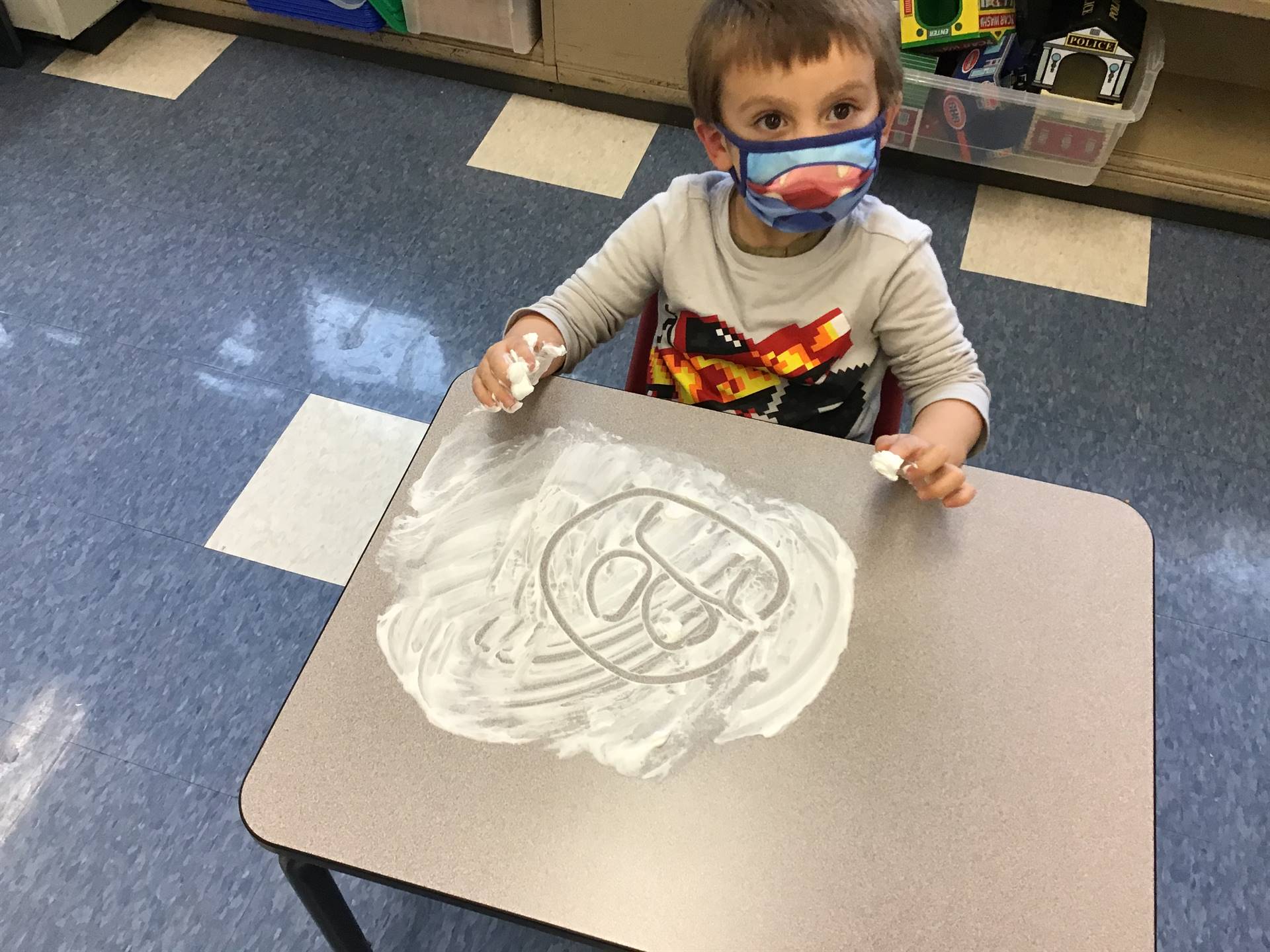 A student draws a sad face in shaving cream.