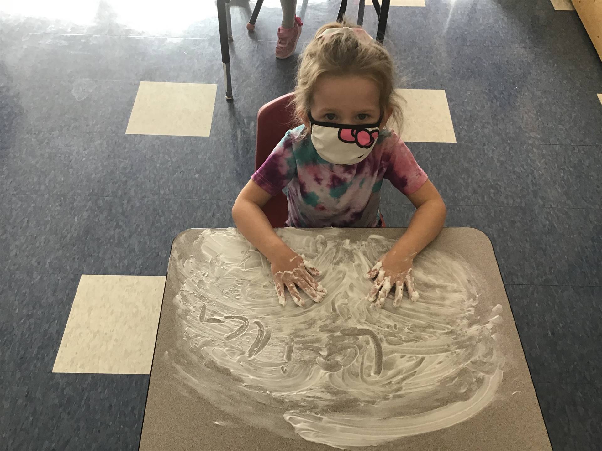 A student draws a sad face in shaving cream.