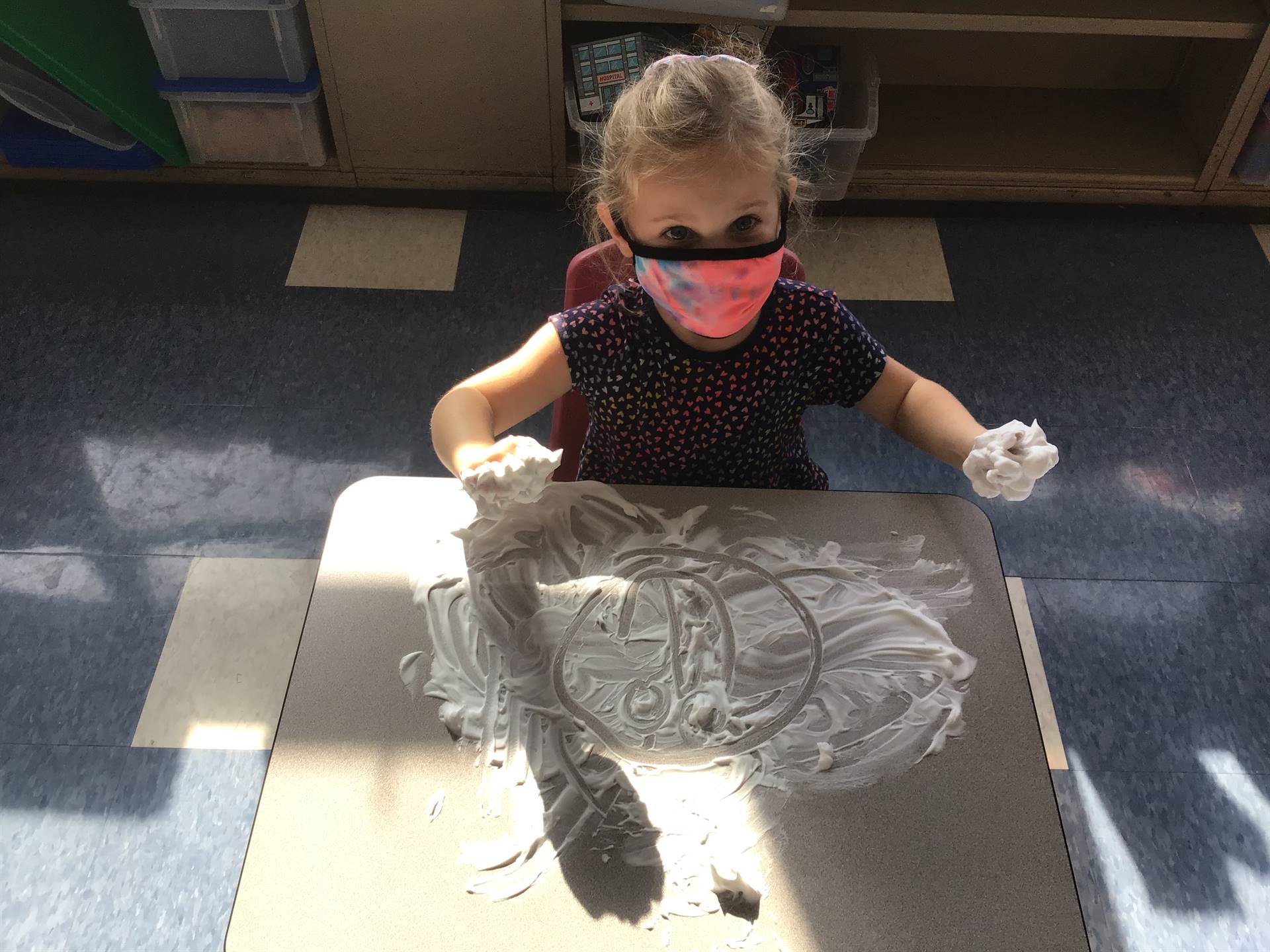A student draws a happy face in shaving cream.