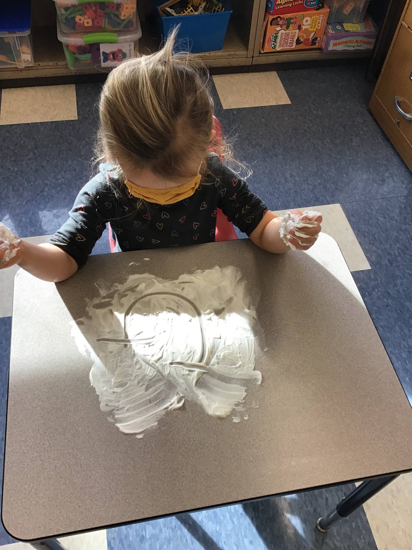 A student draws a sad face in shaving cream.