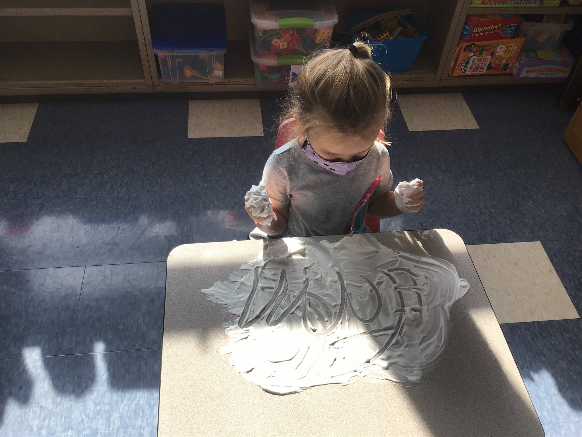 A student draws an angry face in shaving cream.