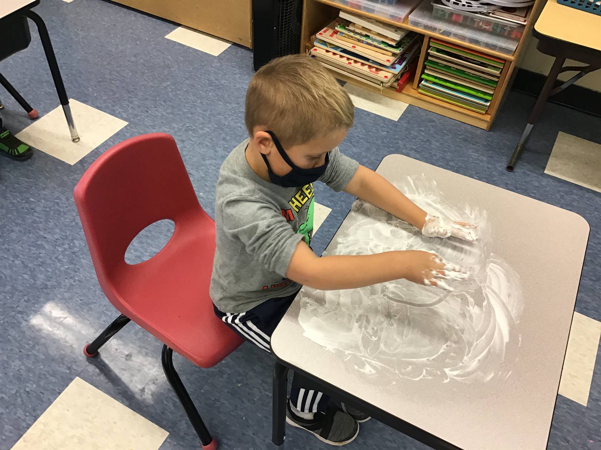 A student draws emotions in shaving cream.