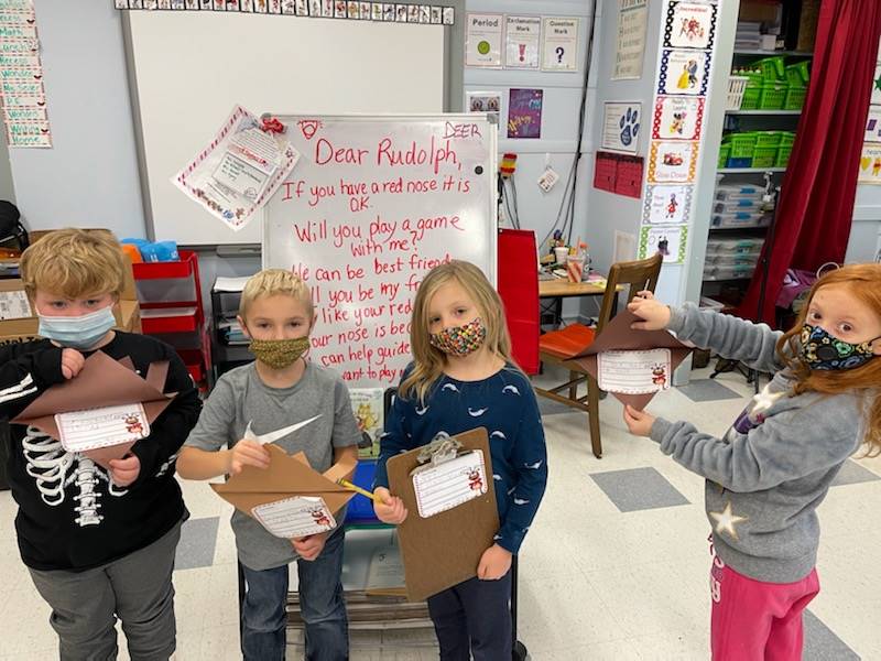 4 students holding reindeer they made.