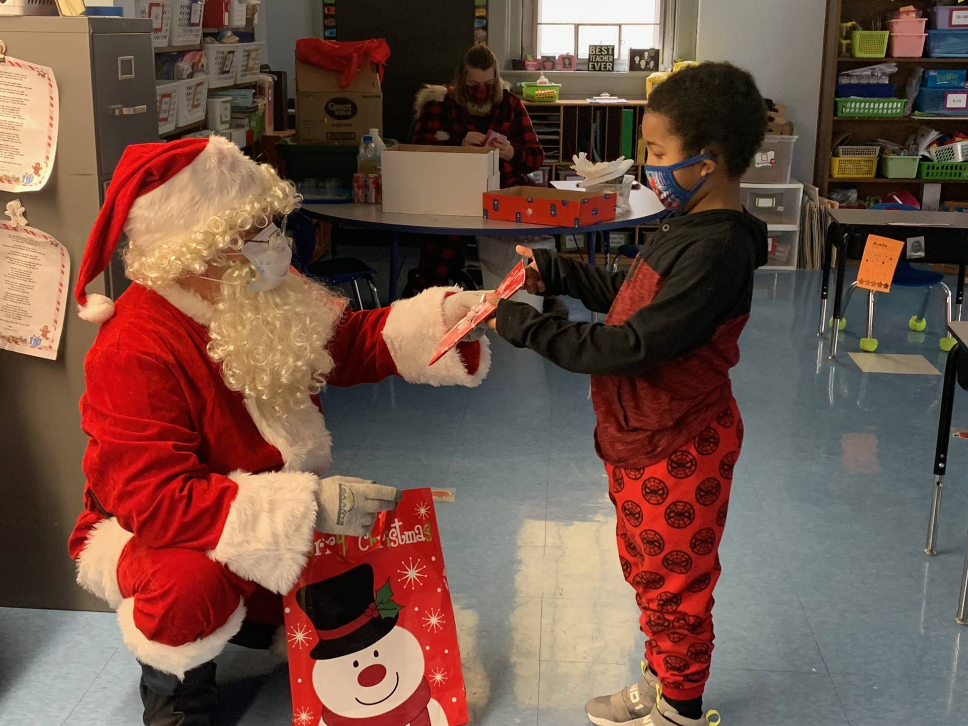 Santa hands a gift to a student.