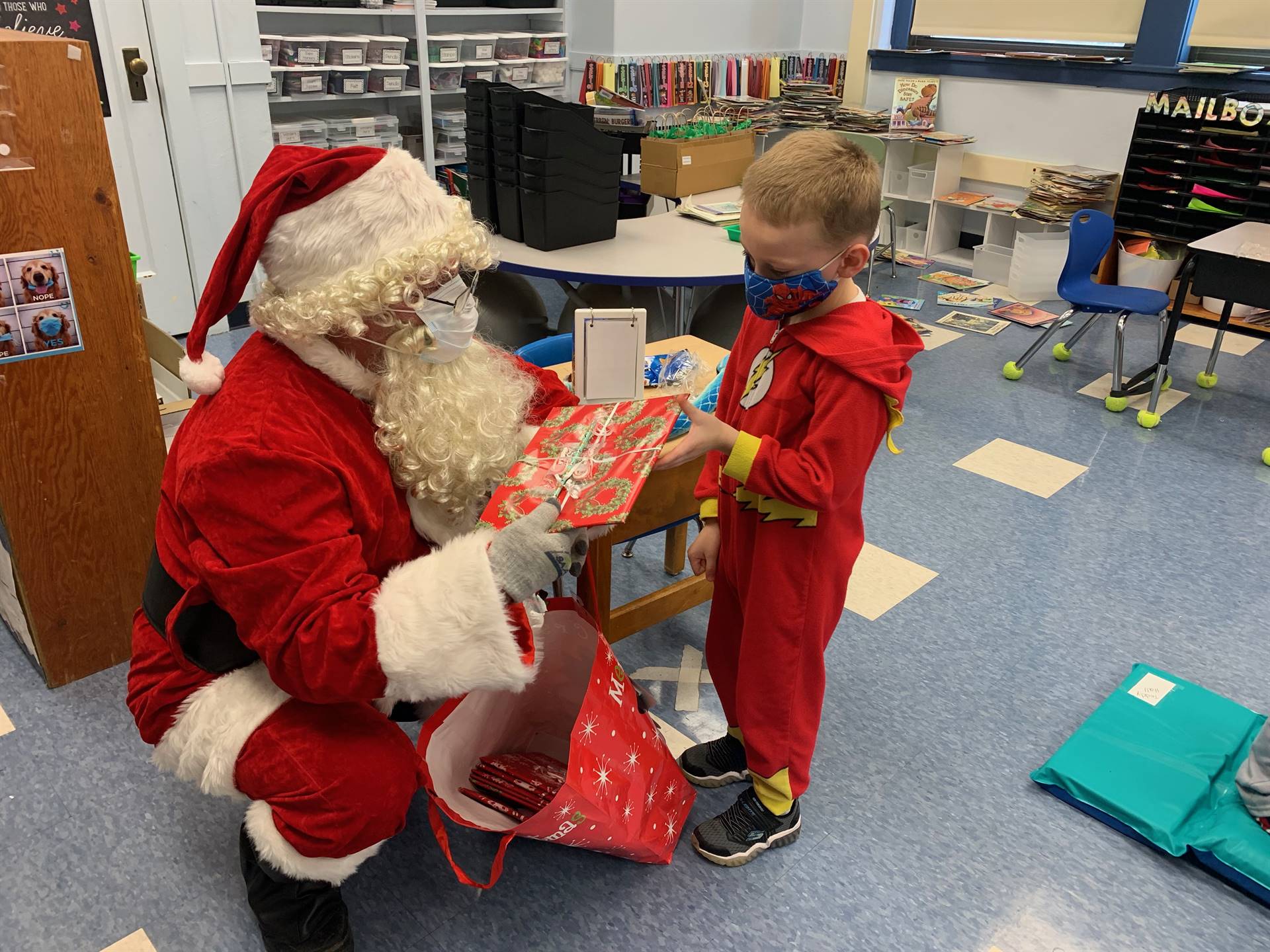 A student dressed up like Flash accepts a Santa gift. 