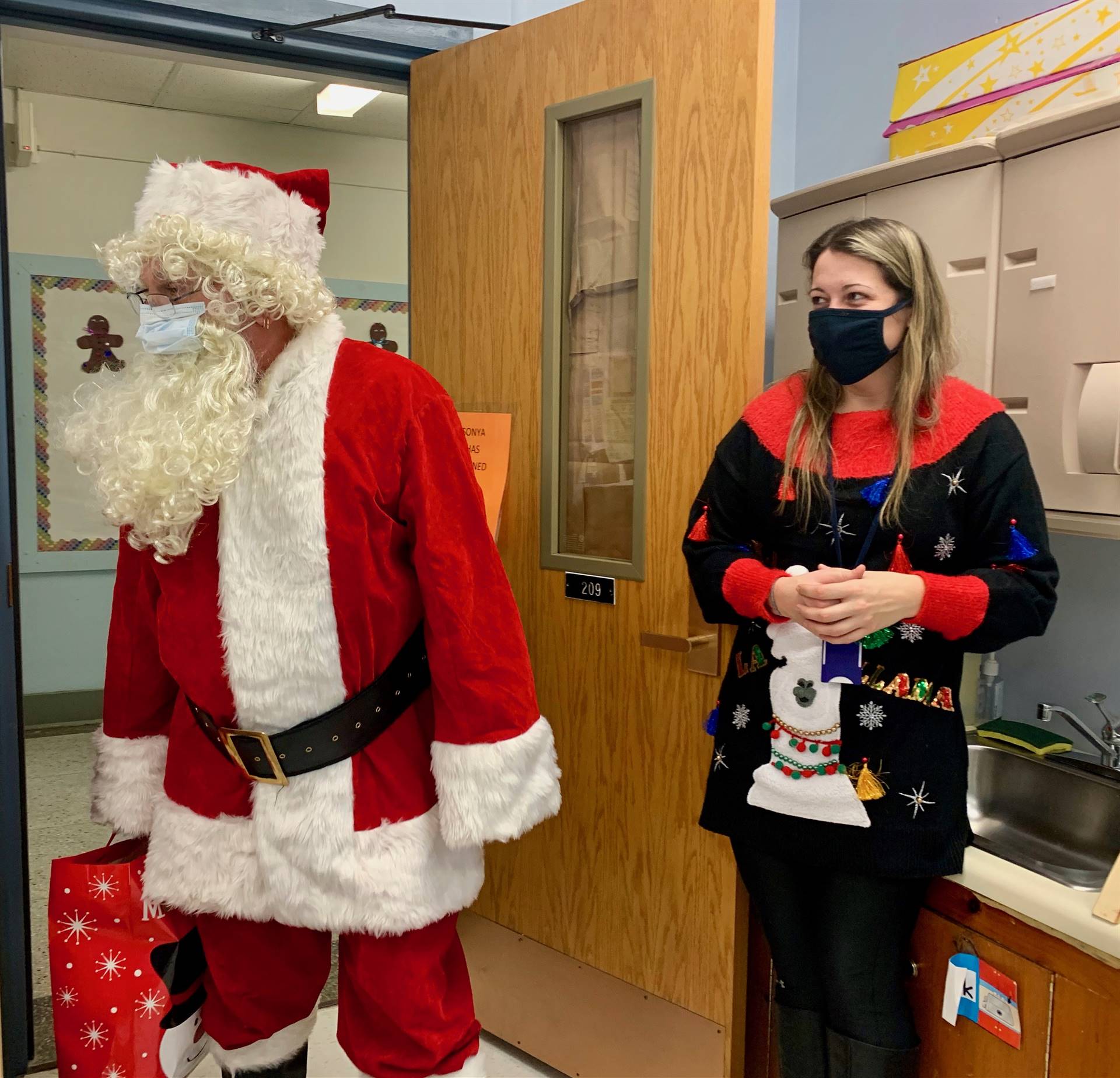 Santa and an elf enter a classroom.
