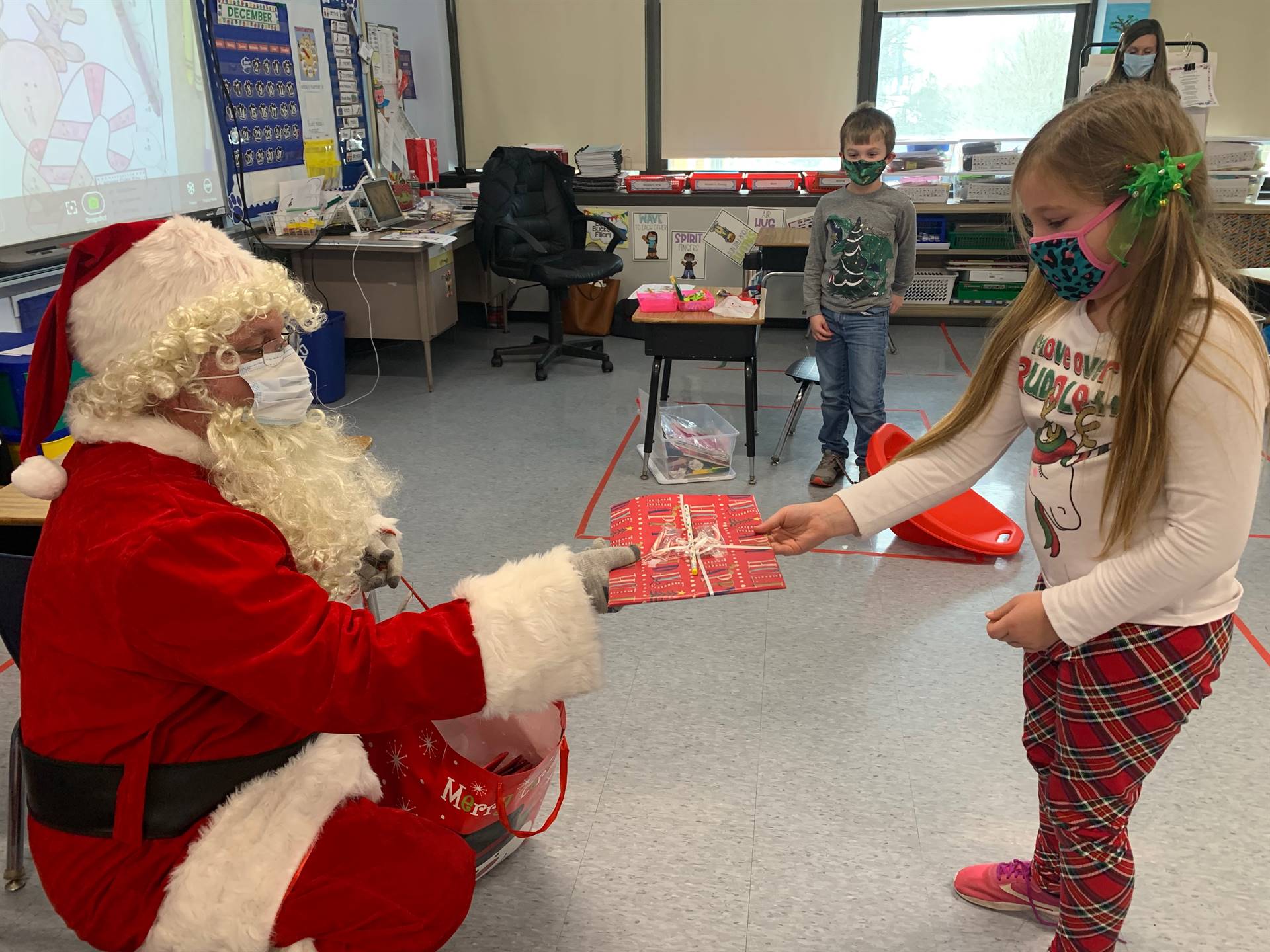 Santa gives a gift to a student.