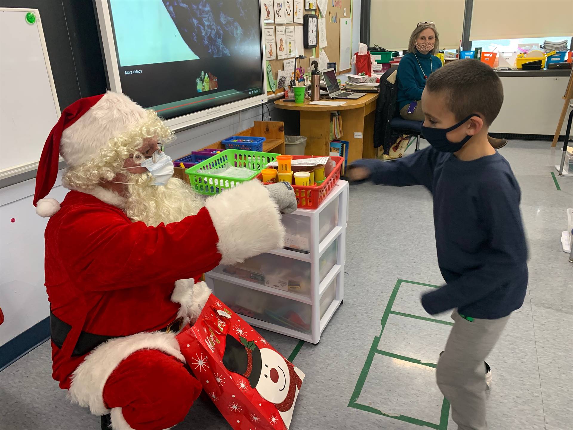 A student does a magic knuckle pound with Santa.