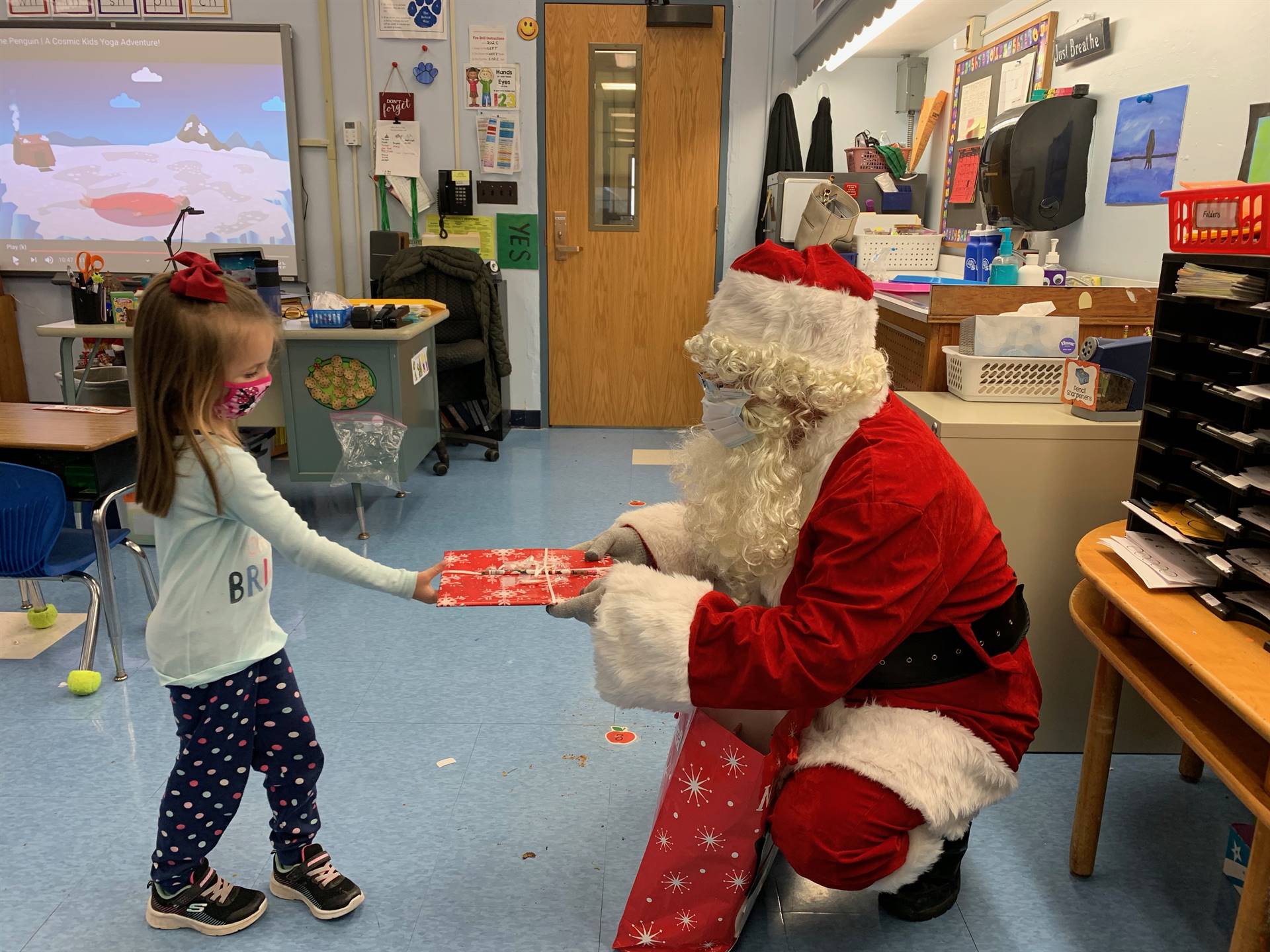 Santa hands a gift out to a child.