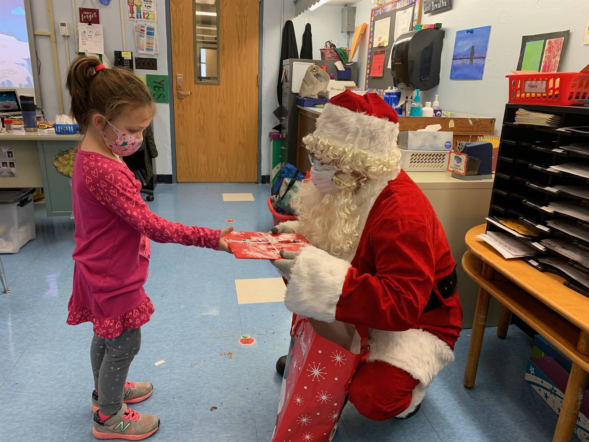 Santa hands a gift out to a child.