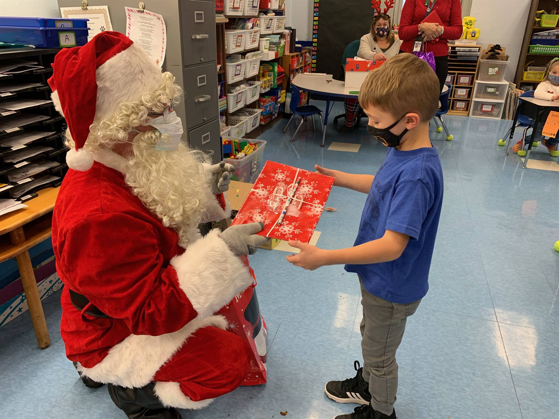 Santa hands a gift out to a child.