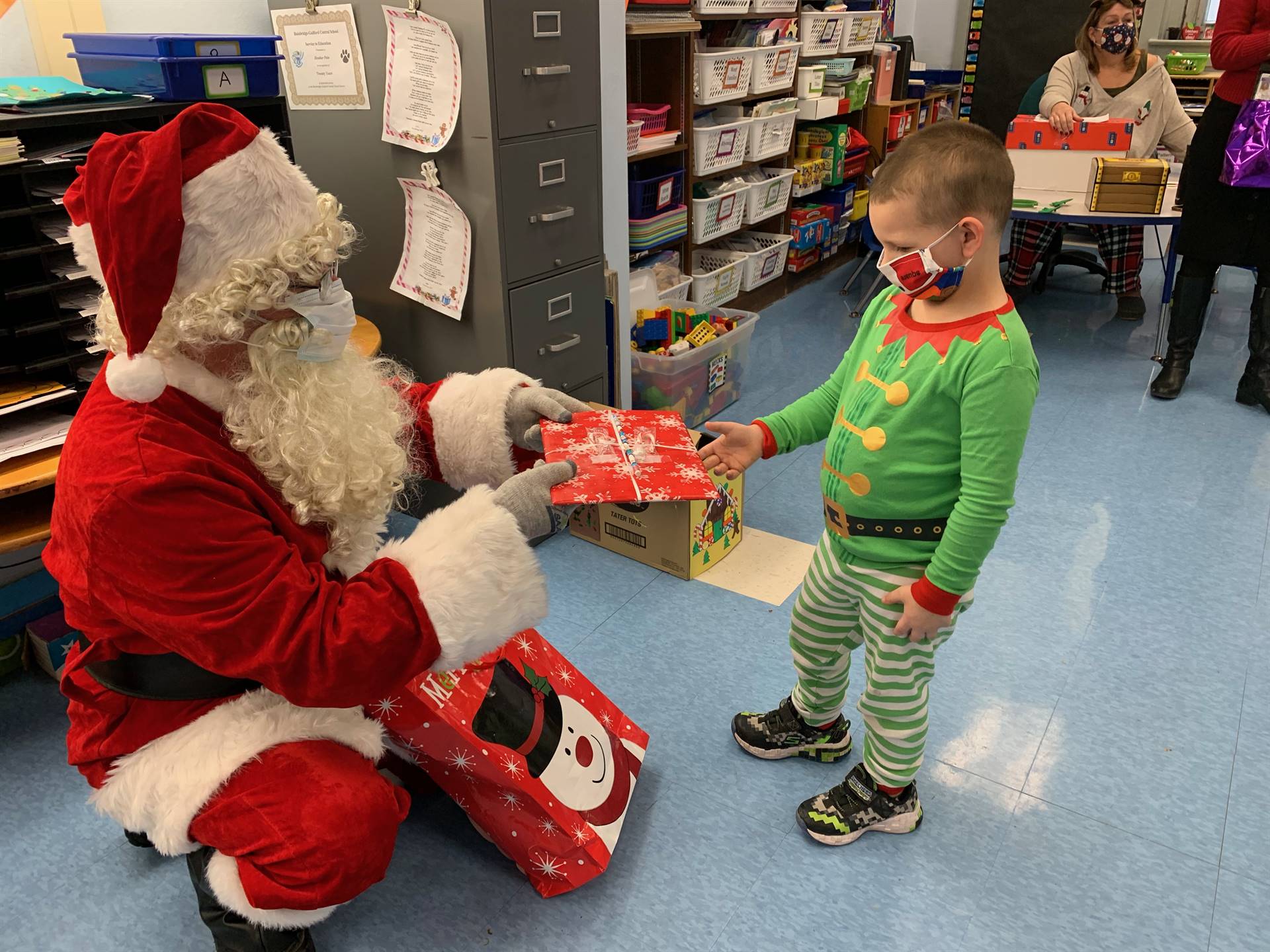 Santa hands a gift out to a child dressed like buddy the elf!
