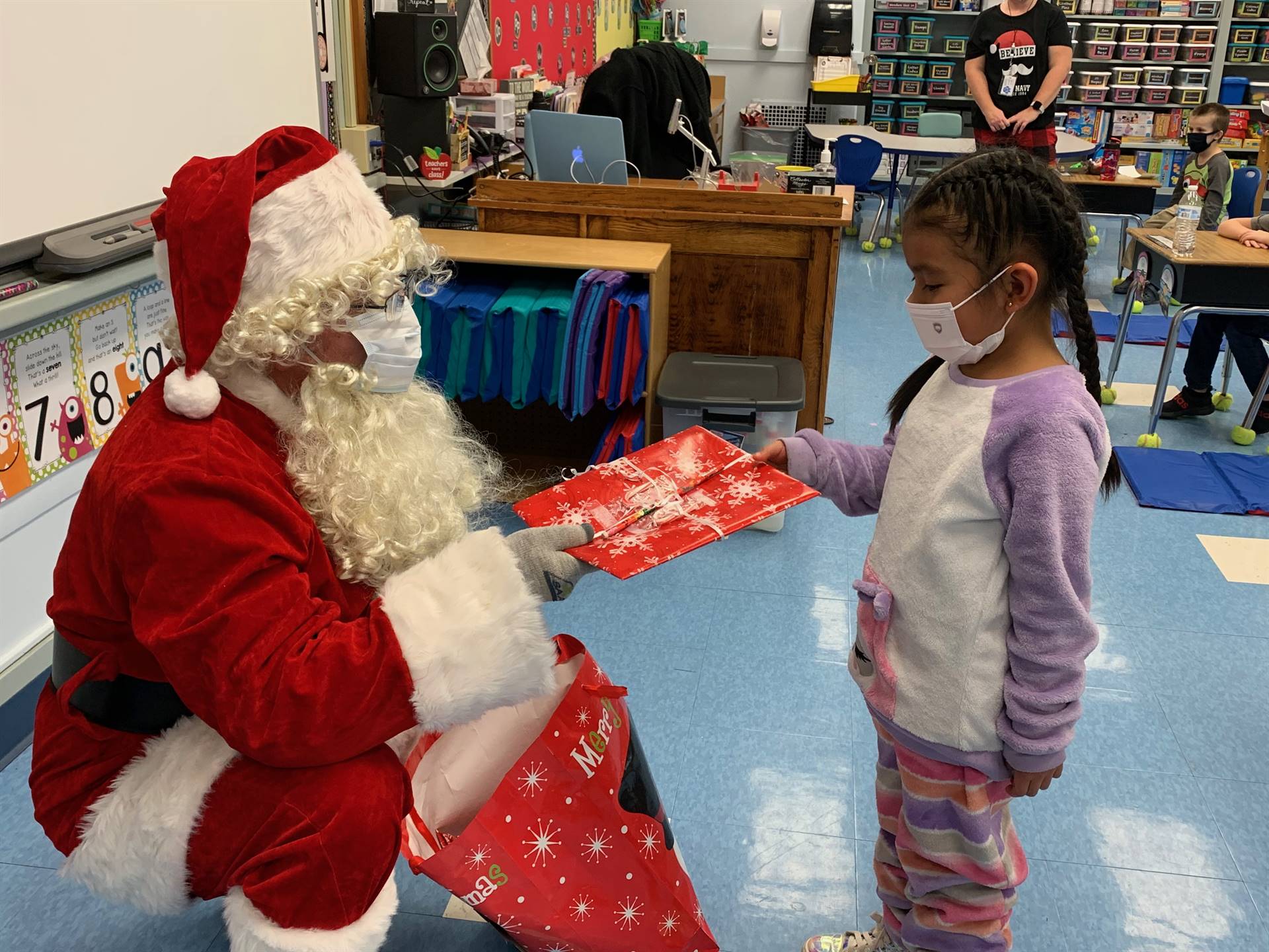 Santa hands a gift out to a child.