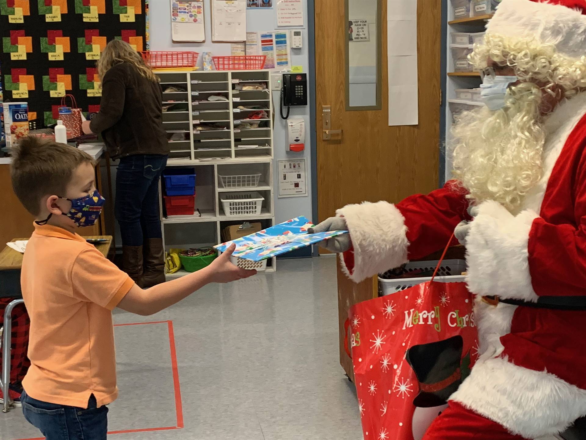 Santa hands a gift out to a child.