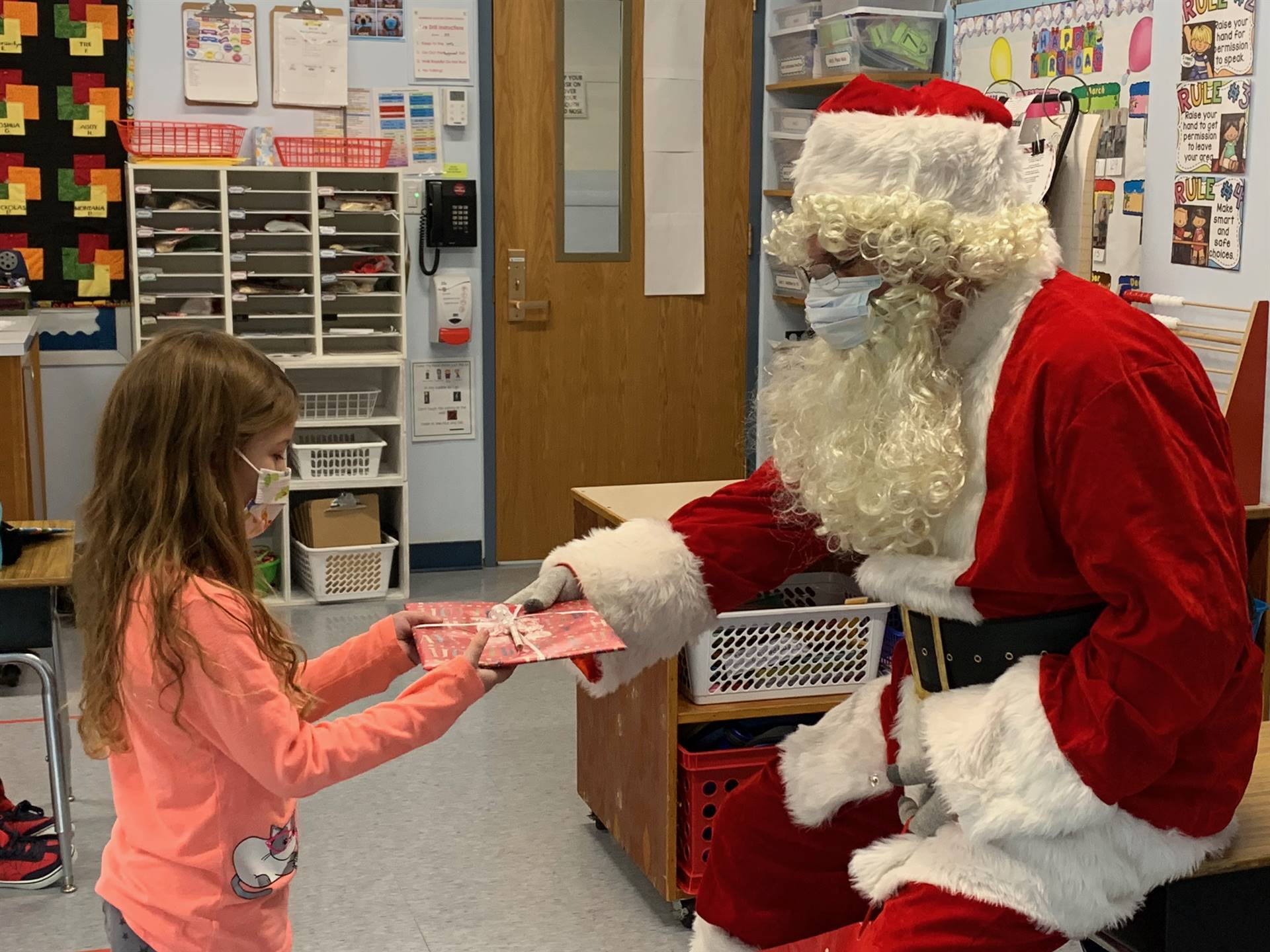 Santa hands a gift out to a child.