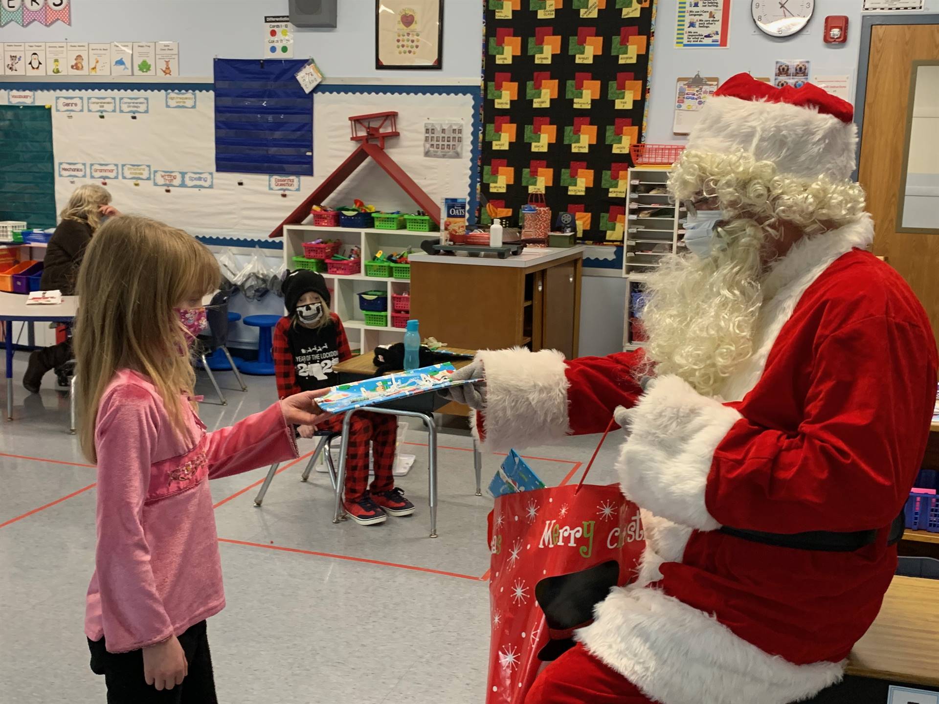 Santa hands a gift out to a child.