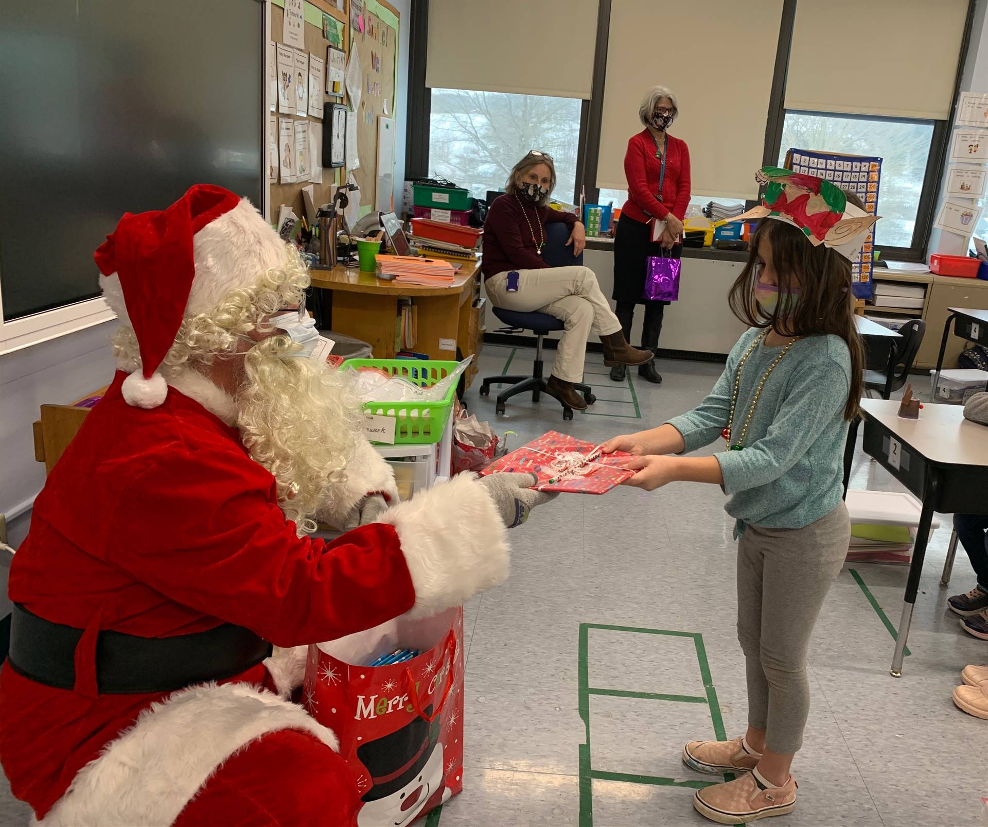 Santa hands a gift out to a child.