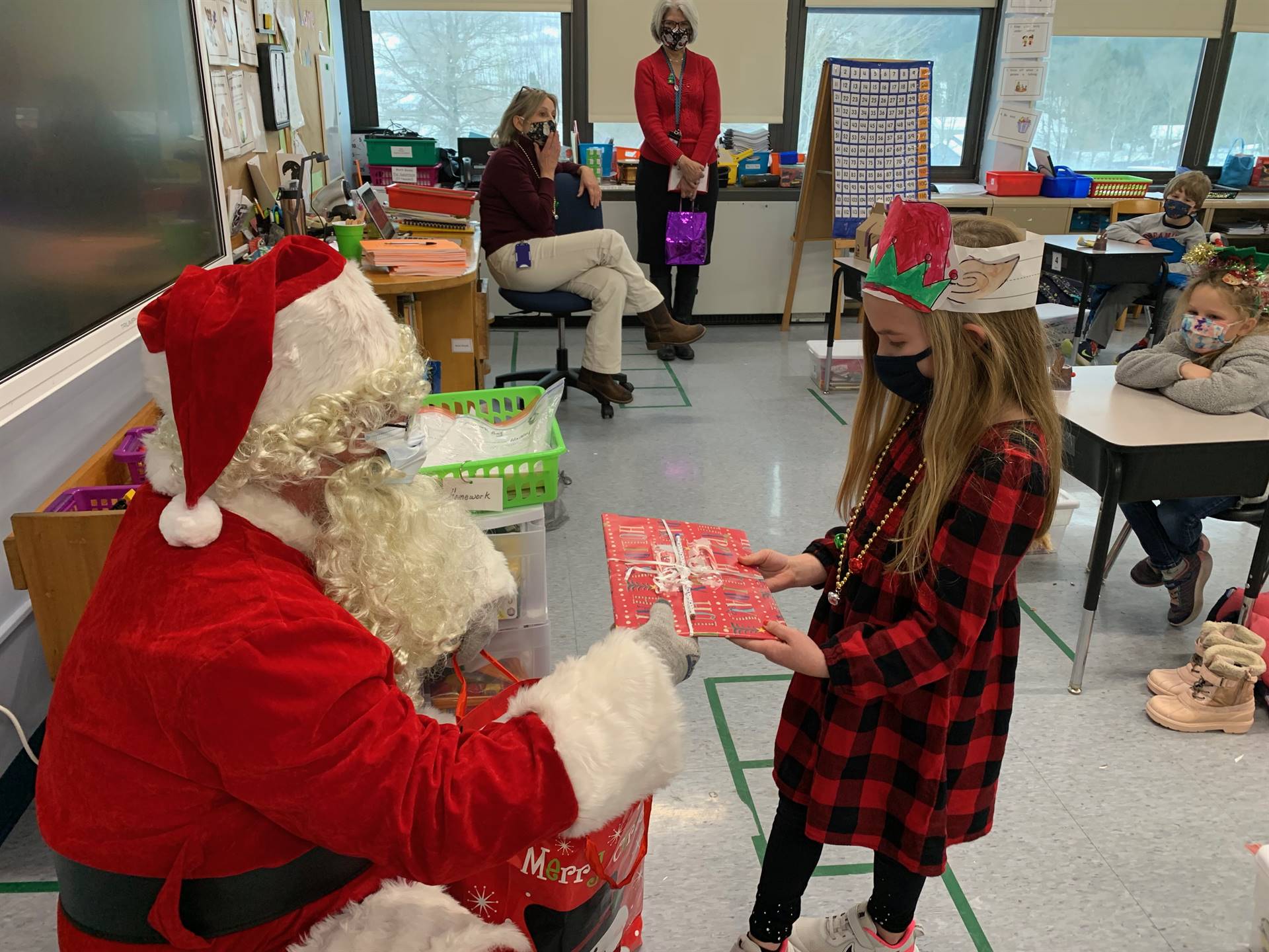 Santa hands a gift out to a child.