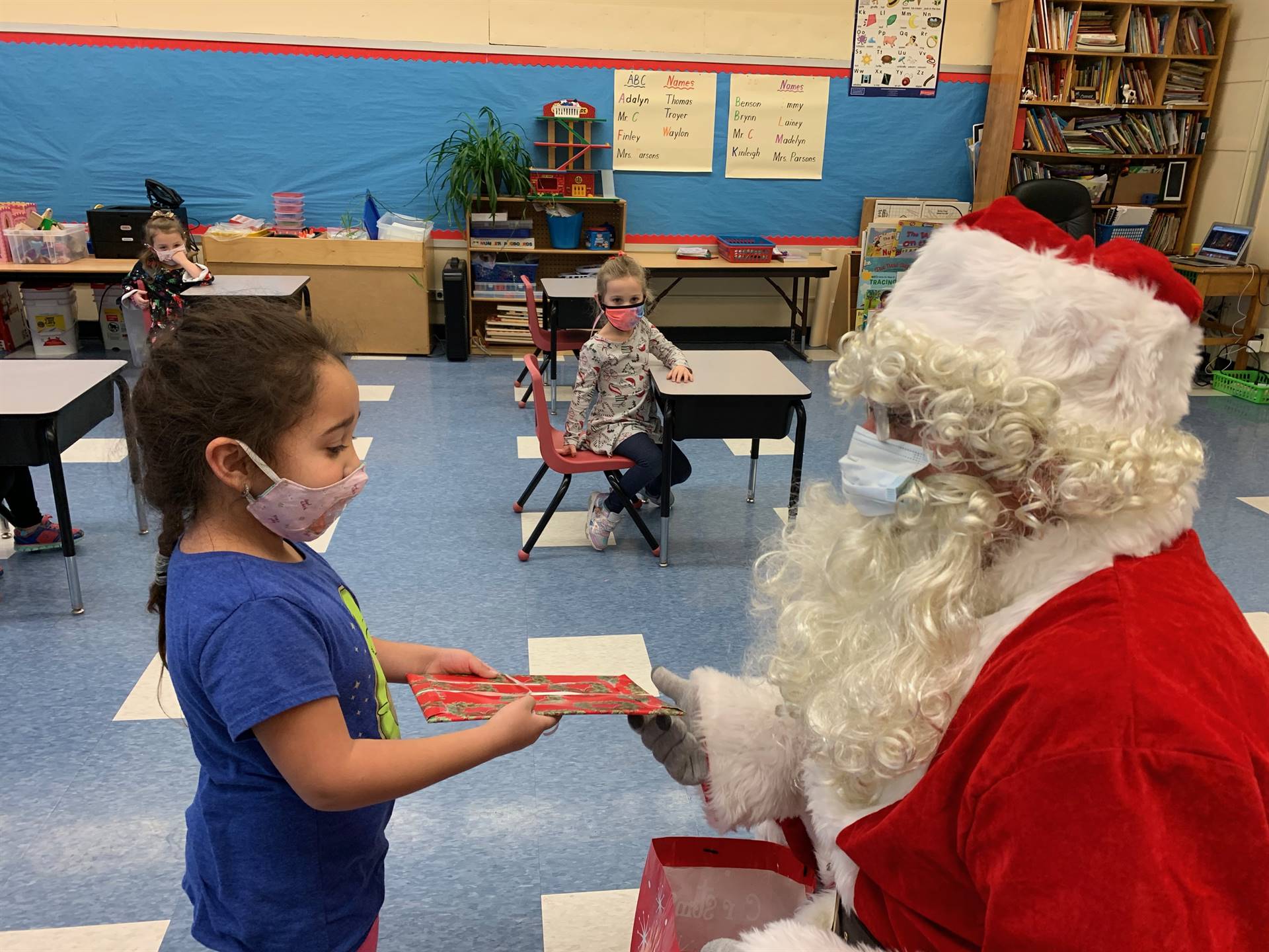 Santa hands a gift out to a child.