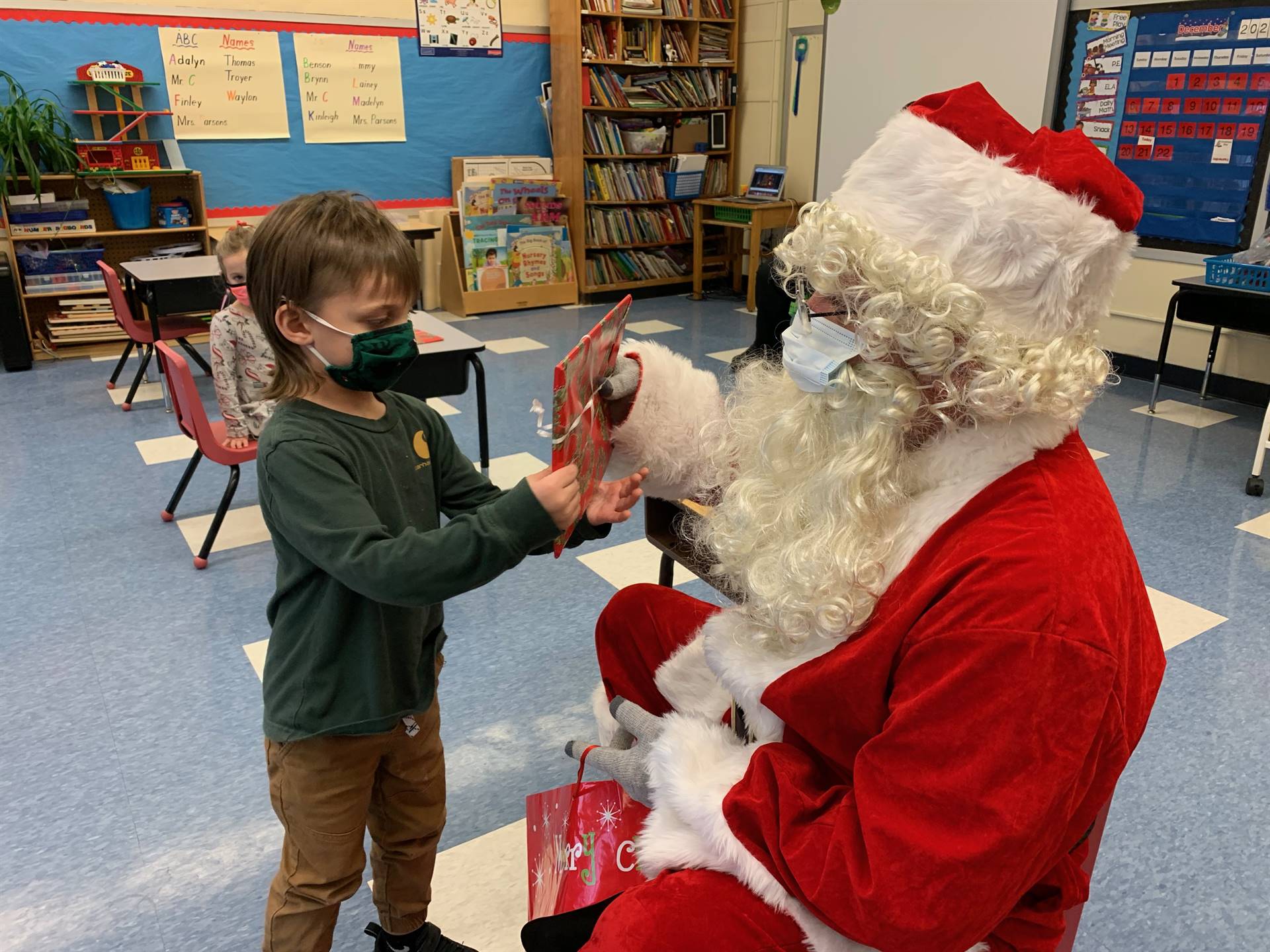 Santa hands a gift out to a child.