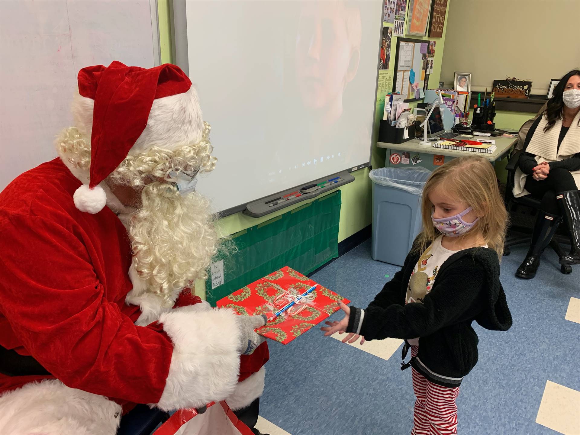 Santa hands a gift out to a child.