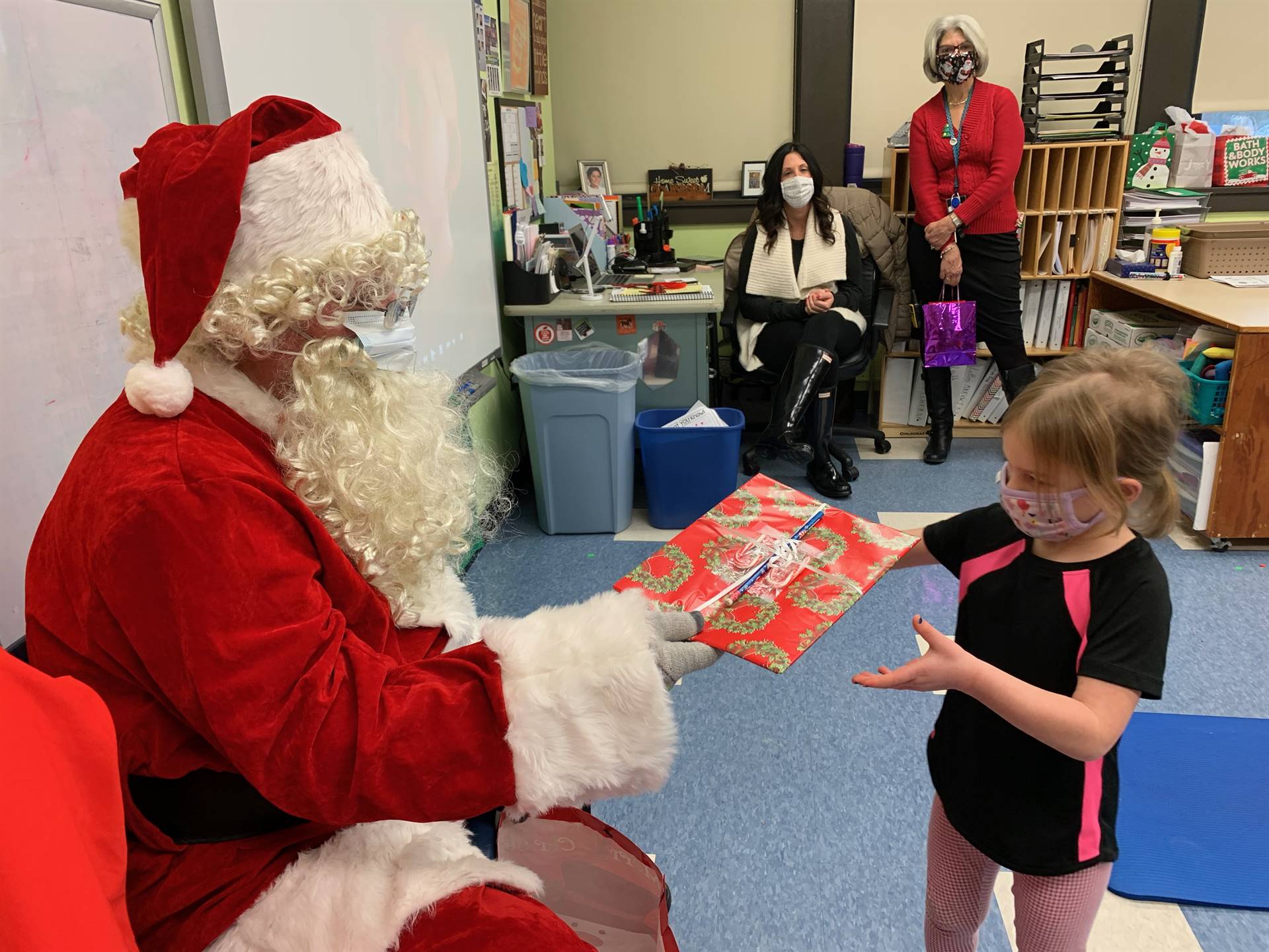 Santa hands a gift out to a child.