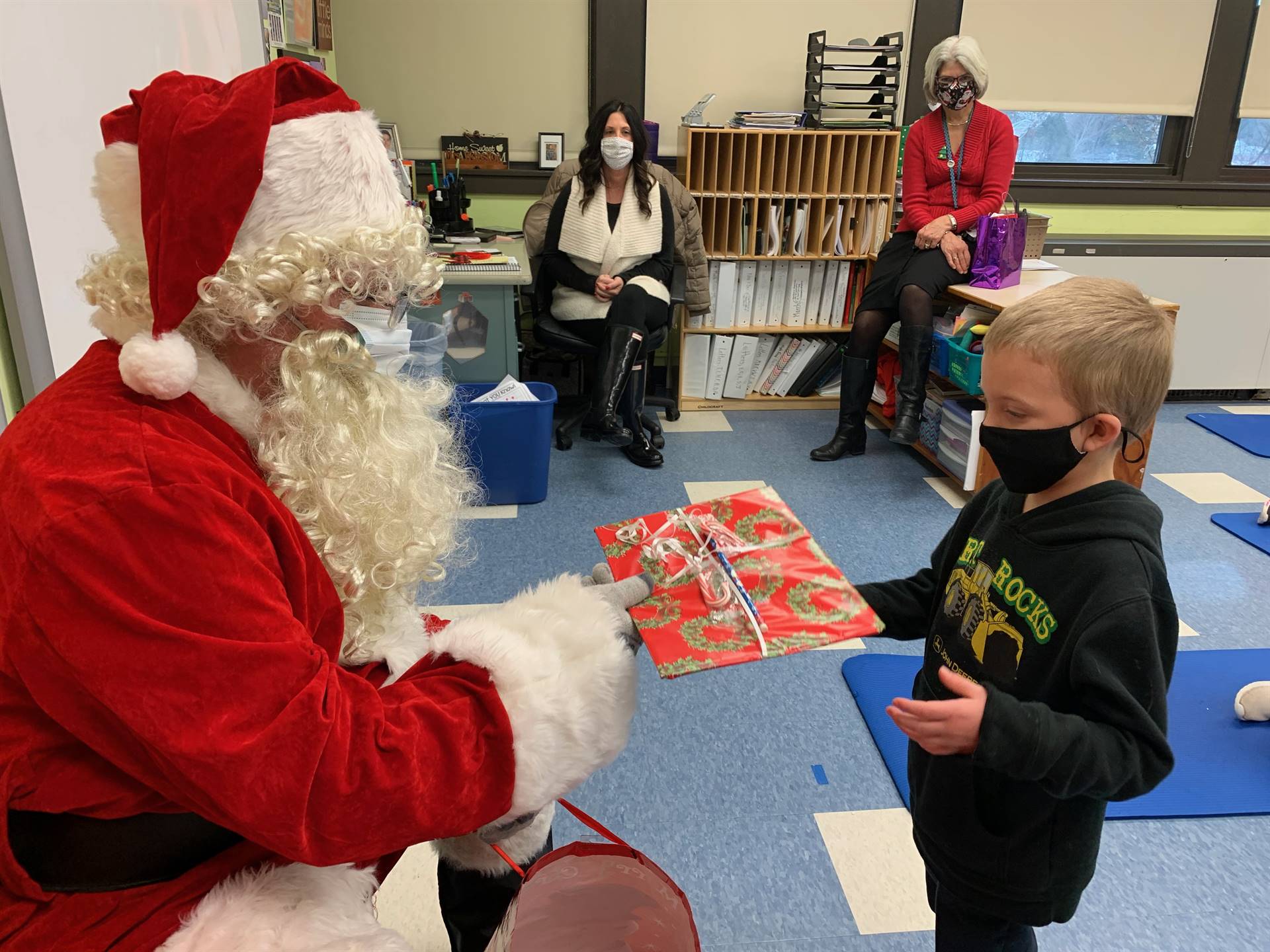 Santa hands a gift out to a child.