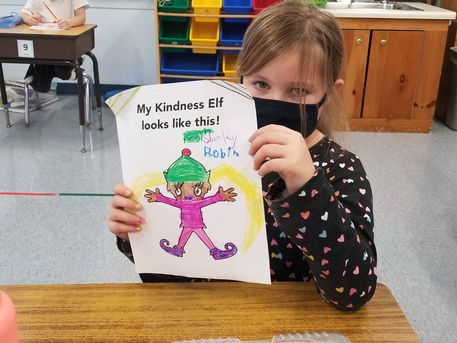 students shows a picture of the kindness elf