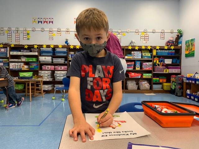 A child coloring his Kindness elf