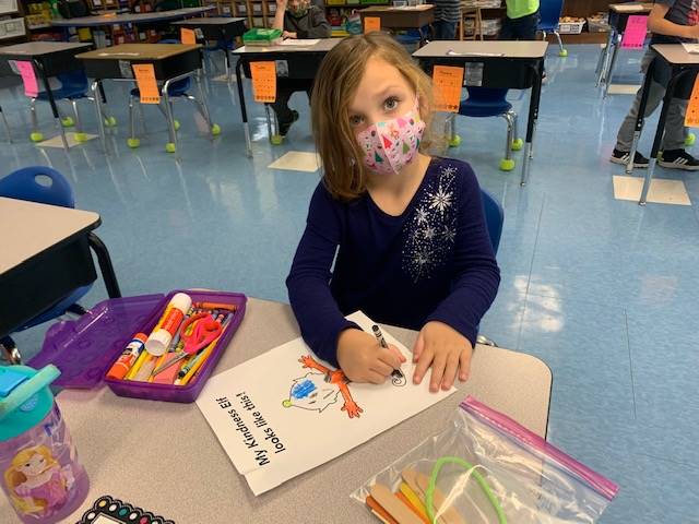 A child is coloring what her kindness elf looks like.