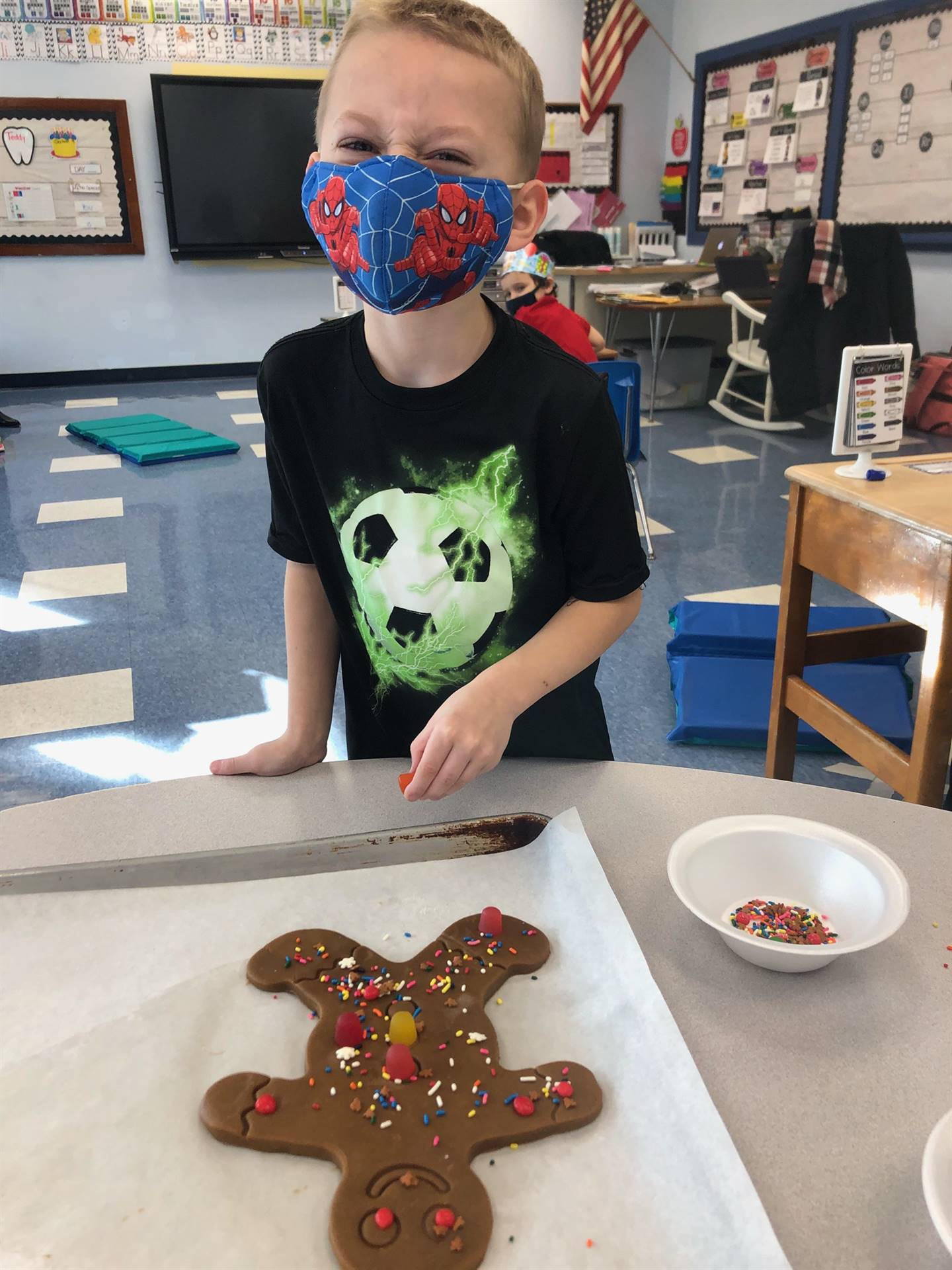 child points to his decorated gingerbread cookie.