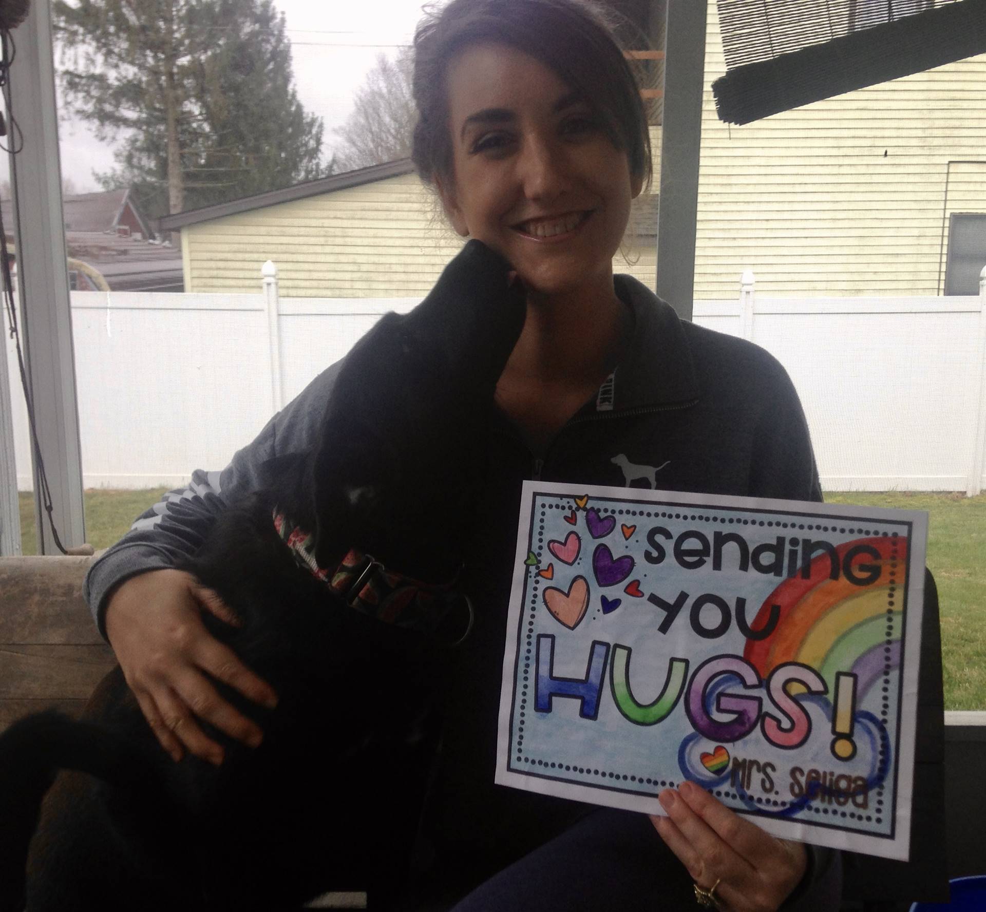 staff member with "sending you hugs" sign