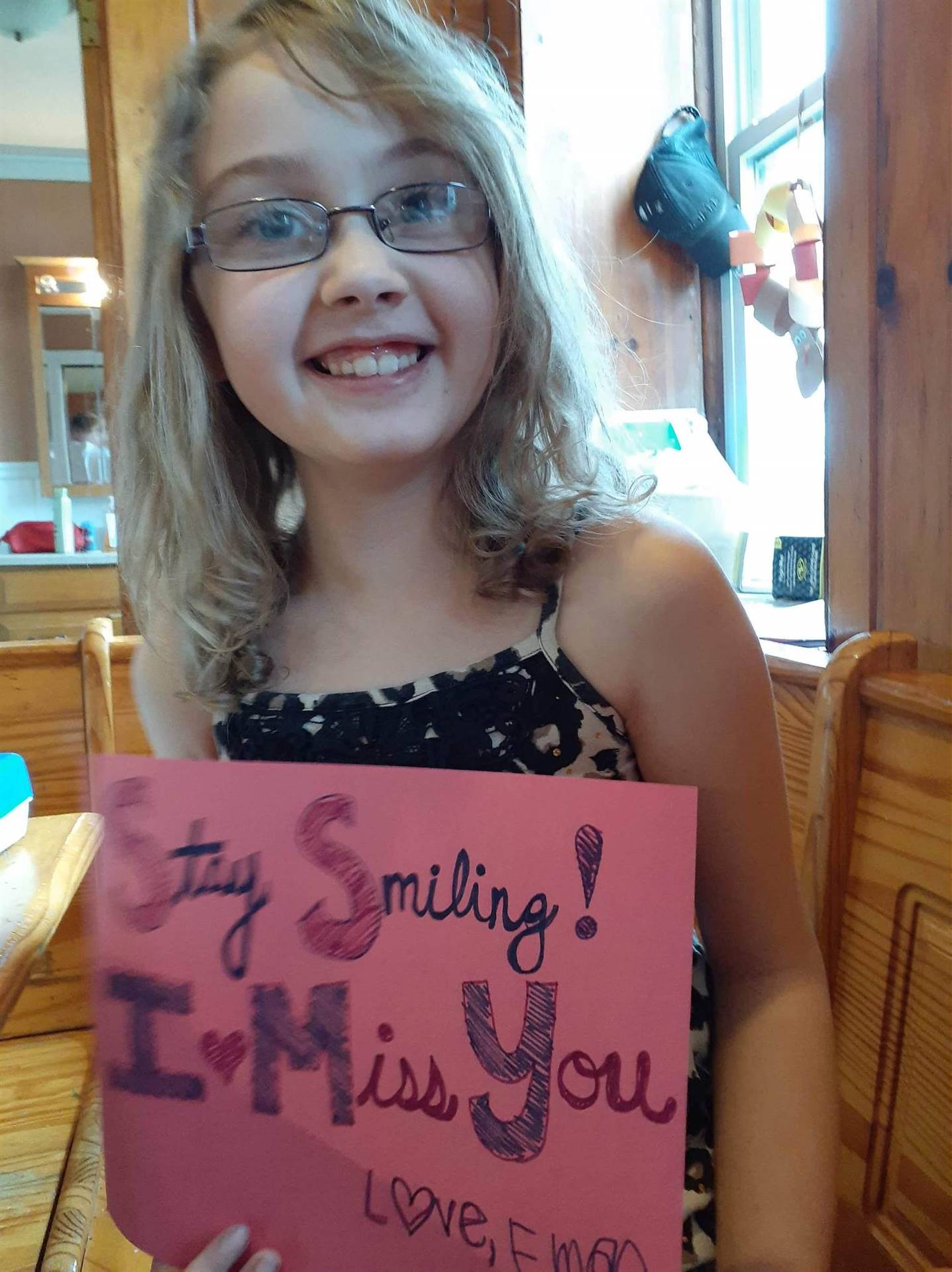Student with "stay smiling I miss YOU sign