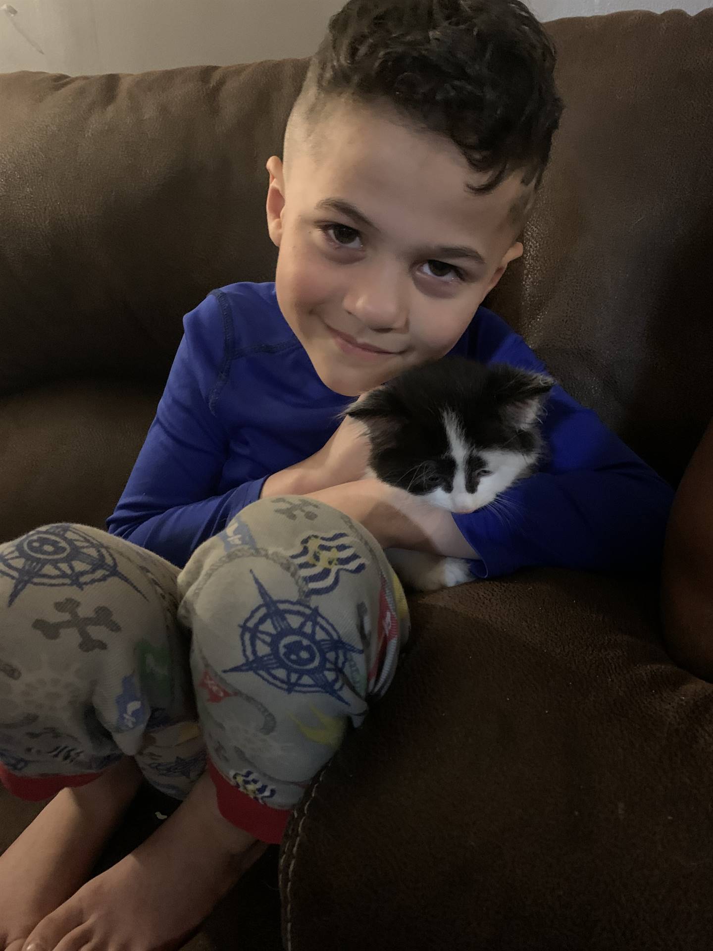 A boy cuddles his kitten.