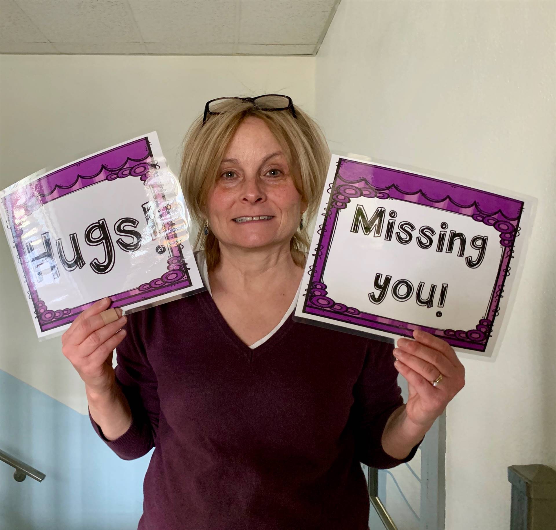 A staff member with signs saying Hugs and Missing you