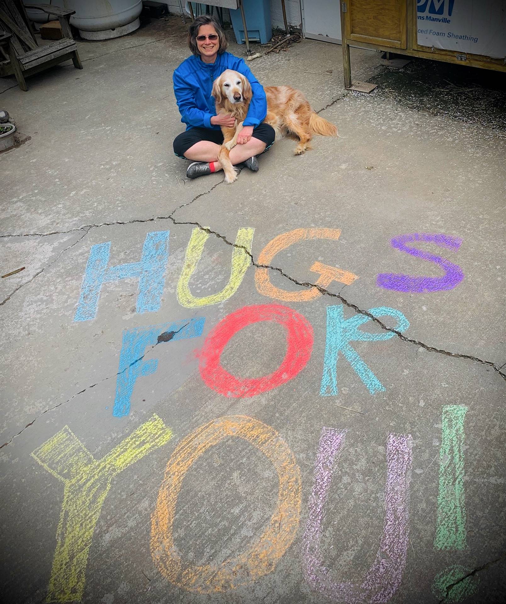 staff member and dog with "HUGS FOR YOU" sign