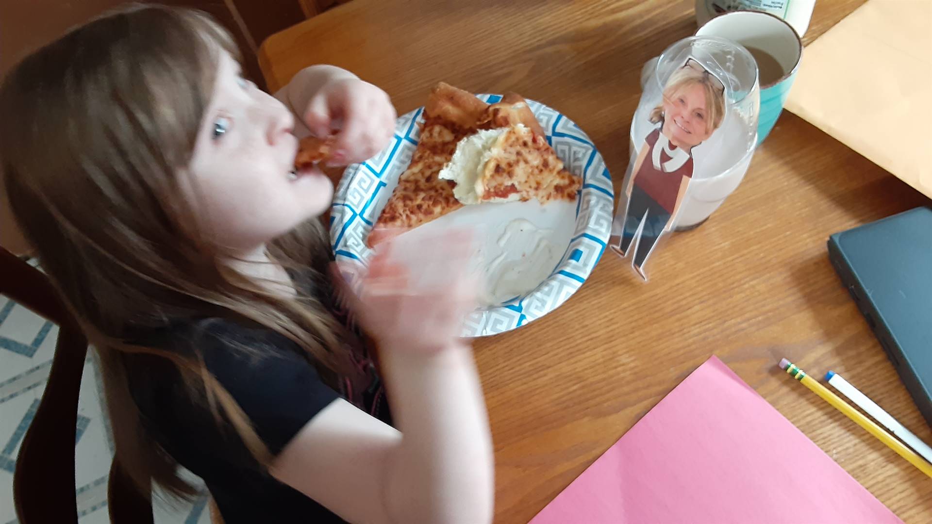 A student eating pizza with her paper doll teacher!