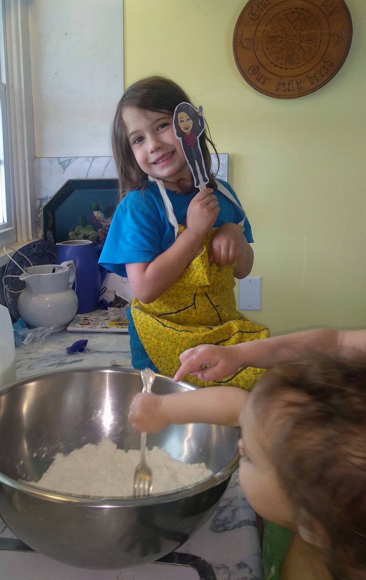 a student bakes with her paper doll teacher.