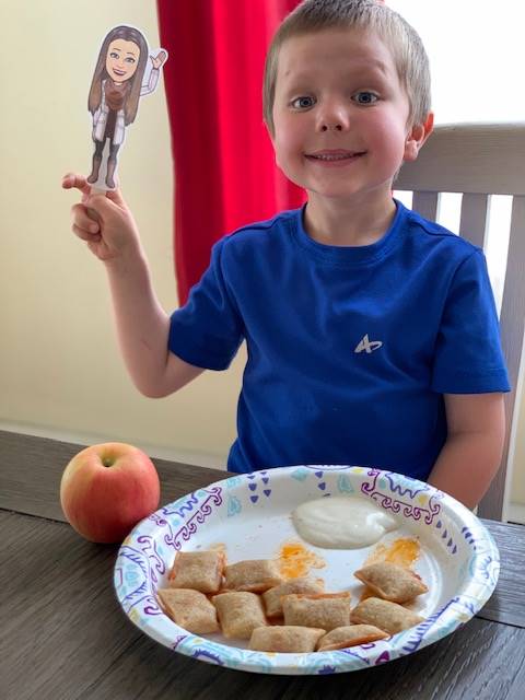 a student holds up paper teacher doll with smiling face.