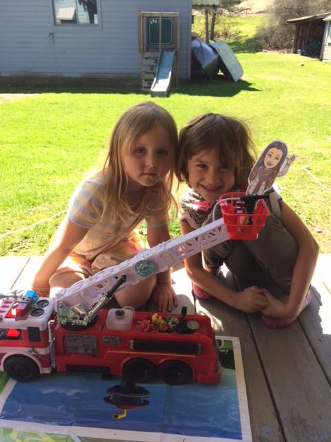 Sisters with paper doll teachers on a toy fire truck!