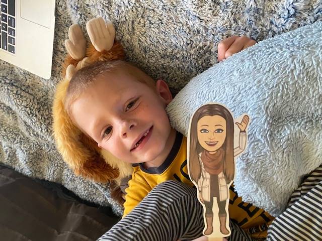 A student is snuggled in a pillow with his paper doll teacher.