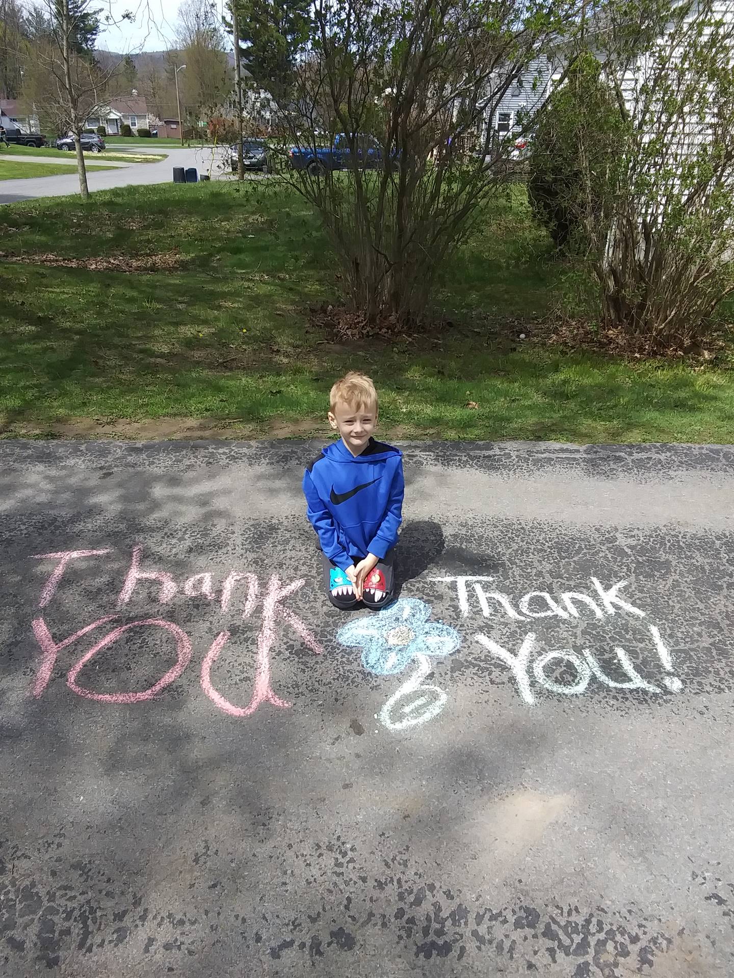 Boy with sidewalk chalk message, "Thank you thank you"