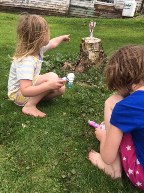 Students with paper teacher on tree stump.