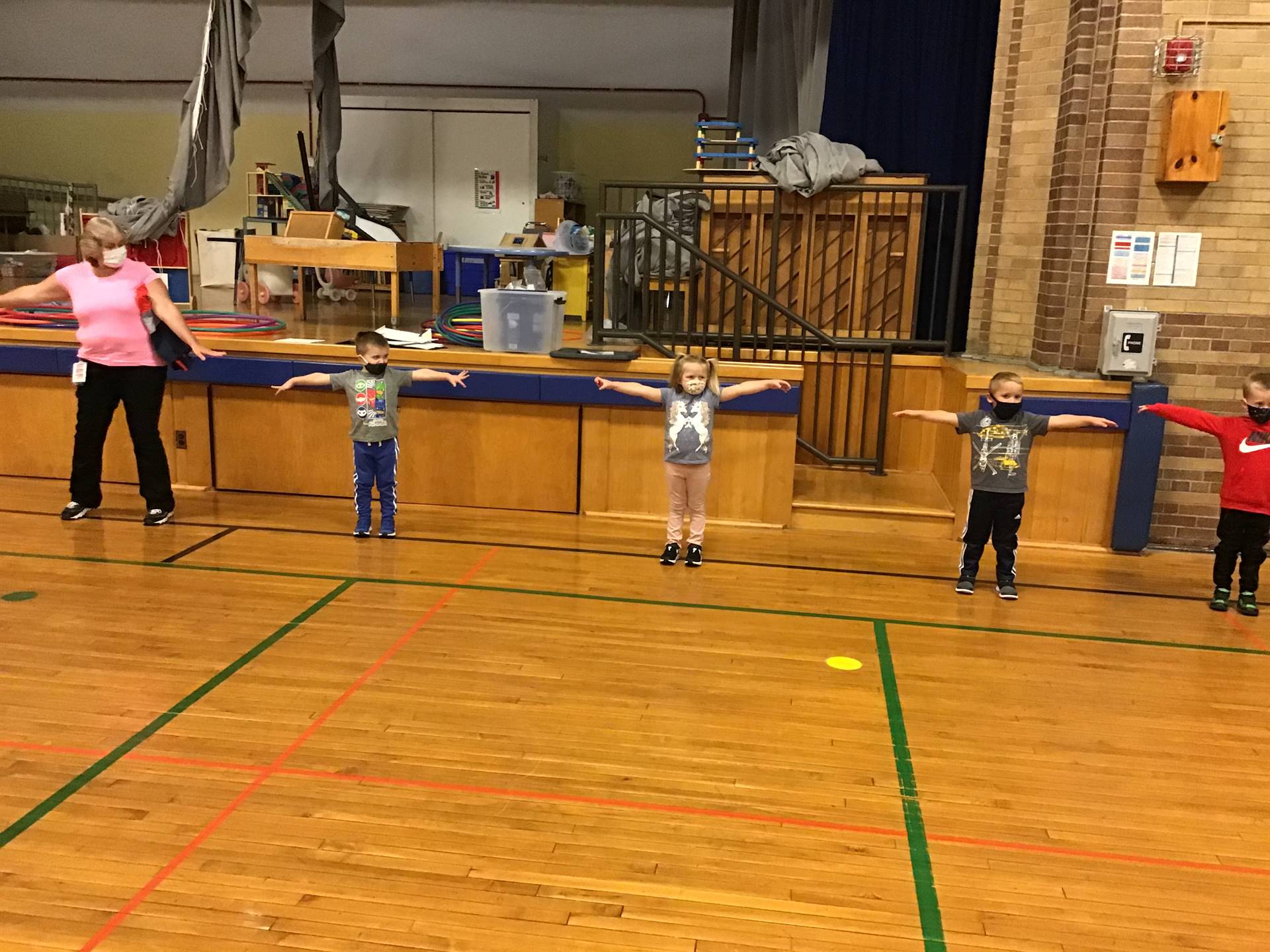 5 students and a staff member  standing with arms outspread to demo social distancing