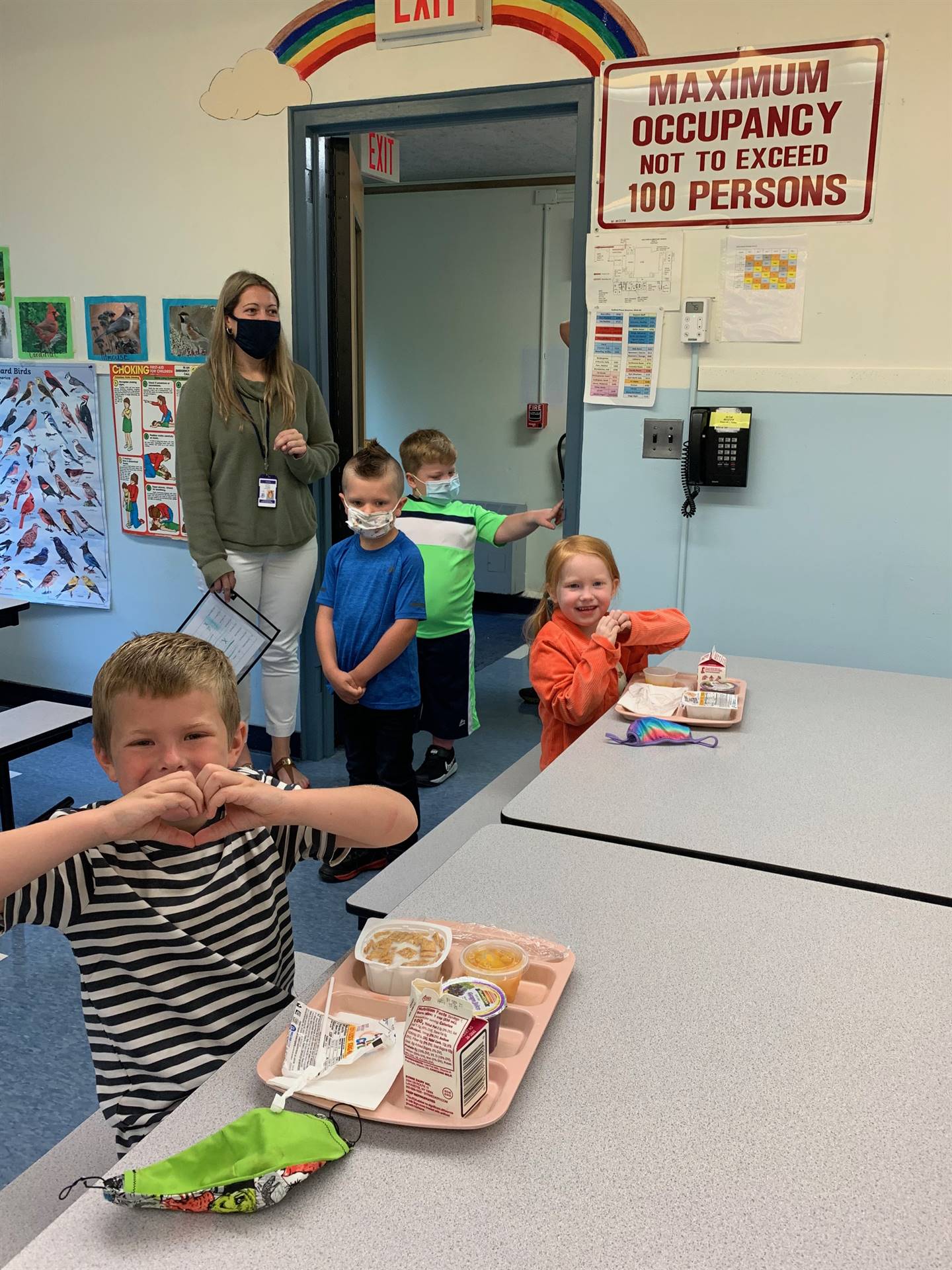 students in cafeteria giving a heart hug