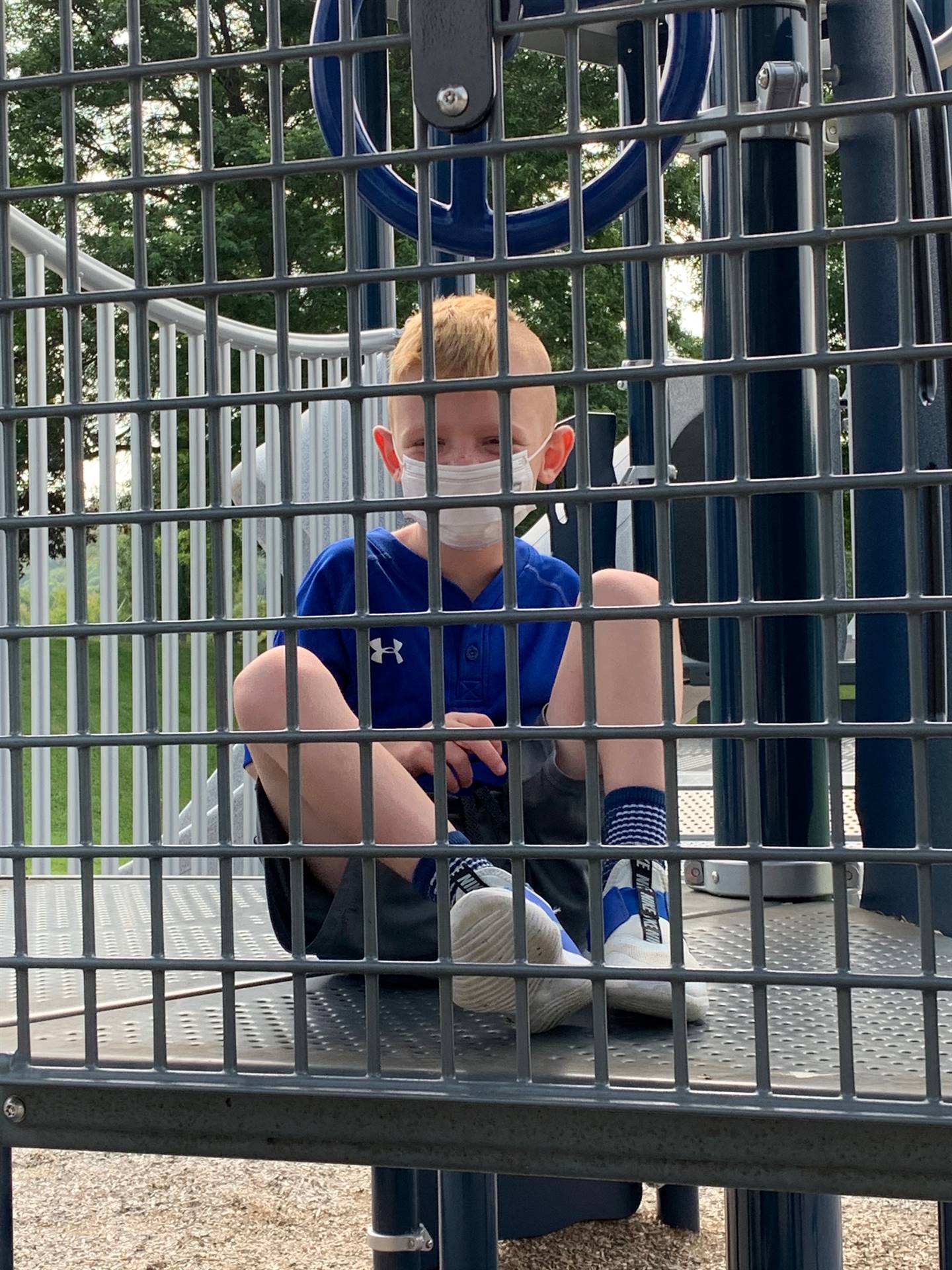 a student peeks out from behind playground bars
