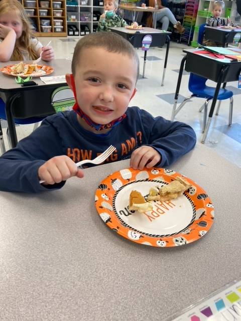 child with pumpkin pie on a plate.