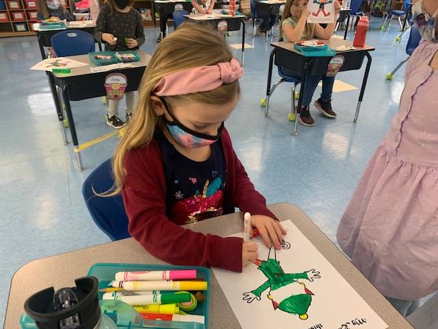 child coloring an elf at her desk. 